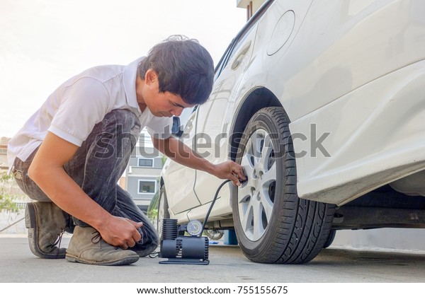 Man checking air pressure and filling air in the\
tires of his car.