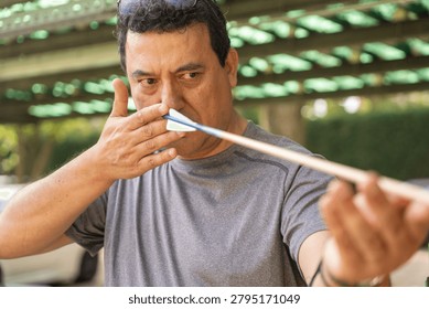 Man checking arrow nock for true flight before archery practice