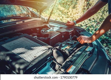 Man Checking A Car Engine Holding A Wrench In A Driveway