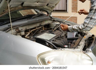 A man checking car mechanical on-site service. Auto mechanic working in the garage. Repair service. checking engine oil level Locate dipstick, automobile car concept.