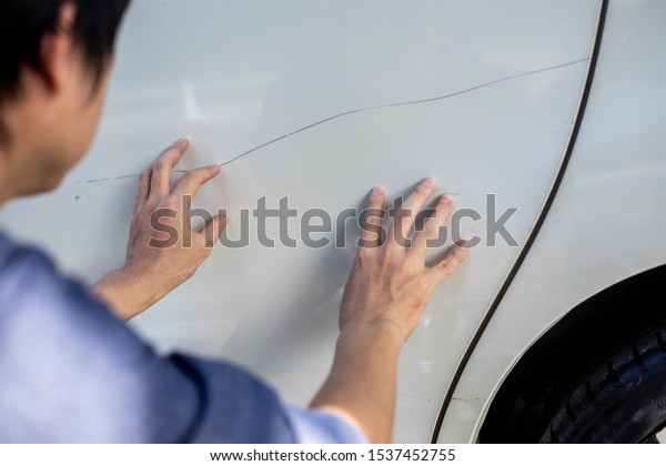 Man checking car scratch dent damage. Car care\
and protection concept.
