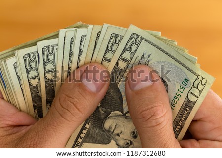 Man checking or counting a handful of 20 USD banknotes in a close up view on his hands over wood
