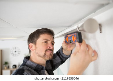 Man Checking Curtain Rail With Spirit Level