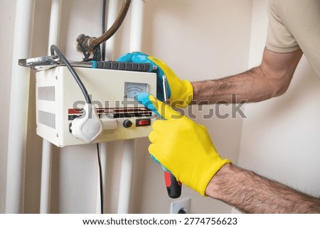 Man checking a electric voltage stabilizer at home. 
