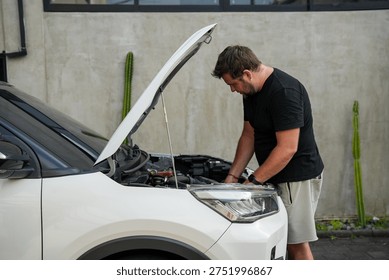 Man checking the engine of a broken car with the hood open. Vehicle breakdown and repair concept, driver inspecting engine after mechanical problem.