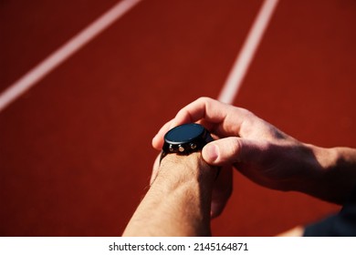 Man Checking Fitness Watch After Exercises At Stadium Rack