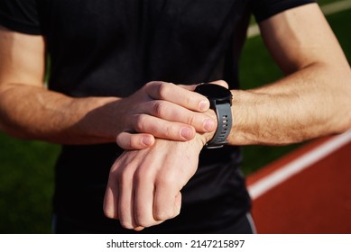 Man Checking Fitness Watch After Exercises At Stadium Rack