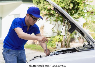 A man checking and fixing a broken car on the side of the road. Problems with broken cars on the highway Man looking under the hood of a roadside assistance concept car. - Shutterstock ID 2206109669