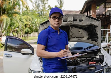 A man checking and fixing a broken car on the side of the road. Problems with broken cars on the highway Man looking under the hood of a roadside assistance concept car. - Shutterstock ID 2206109671