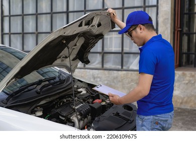 A man checking and fixing a broken car on the side of the road. Problems with broken cars on the highway Man looking under the hood of a roadside assistance concept car. - Shutterstock ID 2206109675