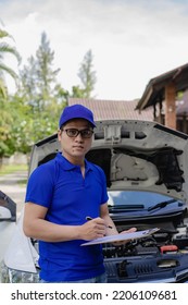A man checking and fixing a broken car on the side of the road. Problems with broken cars on the highway Man looking under the hood of a roadside assistance concept car. - Shutterstock ID 2206109681