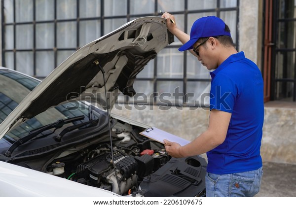 A man checking and\
fixing a broken car on the side of the road. Problems with broken\
cars on the highway Man looking under the hood of a roadside\
assistance concept car.