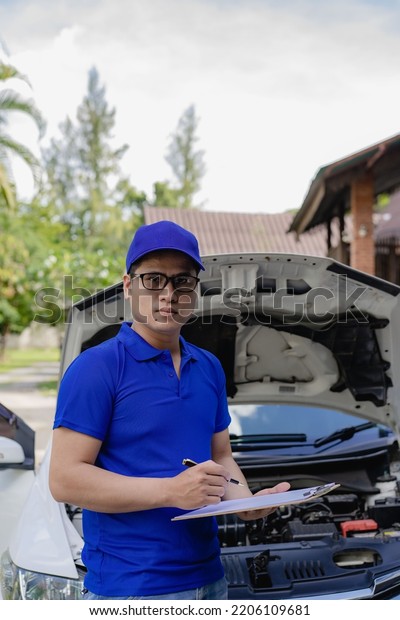 A man checking and\
fixing a broken car on the side of the road. Problems with broken\
cars on the highway Man looking under the hood of a roadside\
assistance concept car.