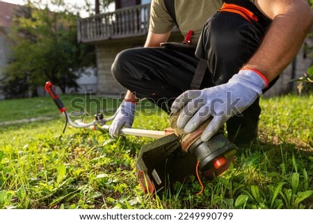 Man checking grass trimmer before star working in his garden maintenance.