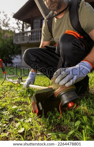 Man checking grass trimmer before star working in his garden maintenance.