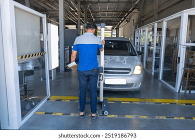 The man is checking the headlights of the car at the vehicle inspection station. - Powered by Shutterstock