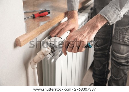 Man checking heating radiator at home.