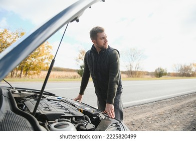 Man checking his broke down car.