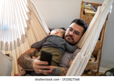 Man Checking His Phone While His Little Baby Son Is Sleeping