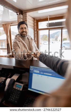 Man checking in at hotel reception, receiving electronic key card for room access