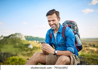 Man Checking Map On Phone While Hiking In The Mountains