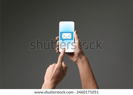 Man checking new message on mobile phone against dark grey background, closeup