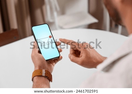 Man checking new message on mobile phone at table, closeup