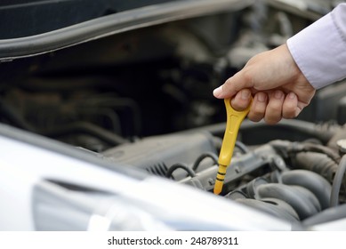 Man Checking Oil In His Car Using Dipstick