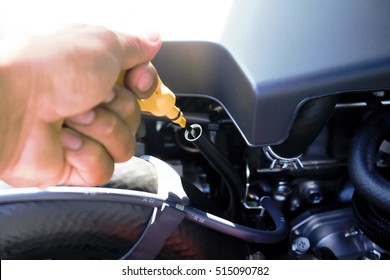 Man Checking Oil In His Car Using Dipstick