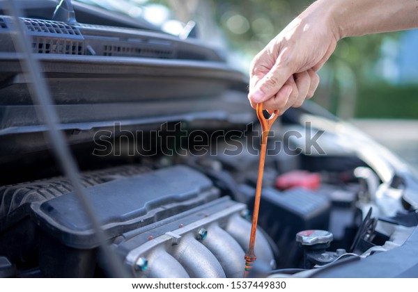 Man checking the oil level in\
car engine, Check and maintenance the oil level in car with\
yourself.
