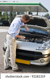 Man, Checking The Oil Level Of The Engine Of His Car At A Gas Station