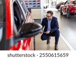 Man checking out wheels and tires of a new car at the dealership. Professional car dealer helping customer buying choosing automobile luxury driving