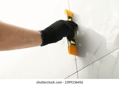 Man checking proper ceramic tile installation with level on wall, closeup. Building and renovation works - Shutterstock ID 1399136456