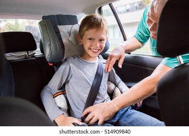 Man Checking Seat Belt Buckling For Child In Safety Seat In Car Before Driving