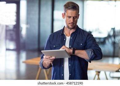 Man checking time while holding digital tablet in creative office - Powered by Shutterstock - Get 15% off with code: PIKWIZARD15