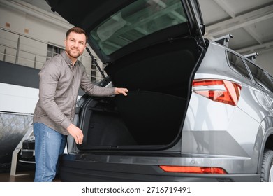 Man checking the trunk space of a new suv in a car dealership, considering cargo capacity before purchase