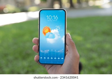 Man checking weather using app on smartphone outdoors, closeup. Data and illustration of sun with cloud on screen