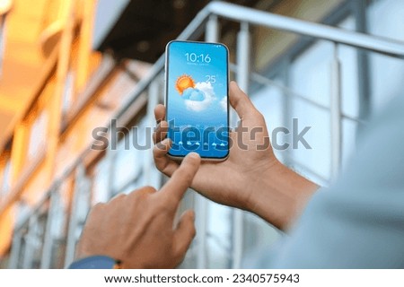 Man checking weather using app on smartphone outdoors, closeup. Data and illustration of sun with cloud on screen
