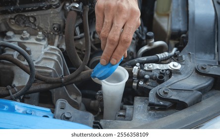 Man checking the windshield washer fluid of a car.