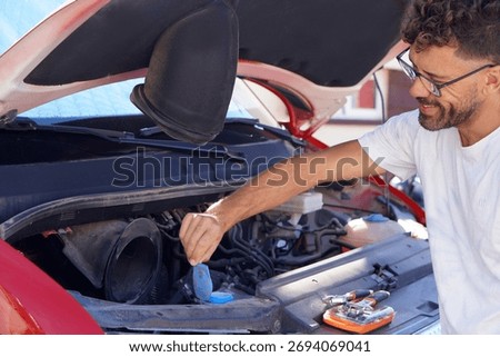 Man checking the windshield washer fluid level in a camper van before starting his vacation