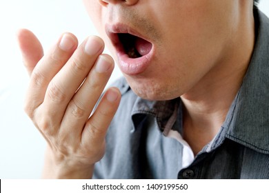 A man checks for bad breath and breathes with his hands. he has bad breath Concept of oral and dental health
