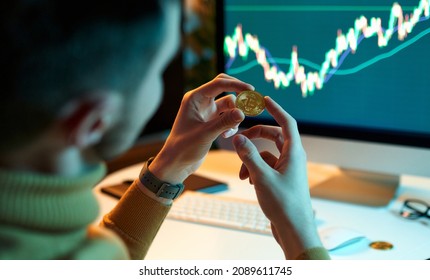 The man checks and controls the financial database on international exchanges holding gold bitcoins. Crypto trader investor analyst looks at laptop screen, analyzes financial chart data - Shutterstock ID 2089611745