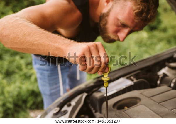 A man\
checks the oil in the car, a car\
breakdown