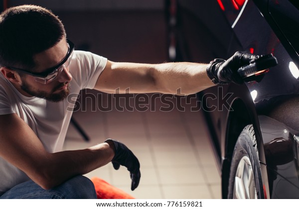 man checks the\
polishing with a torch