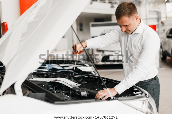 man checks\
the presence of oil in the car\
close-up
