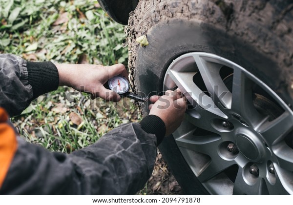 a man checks the pressure in the tires of the car\
with a pressure gauge.