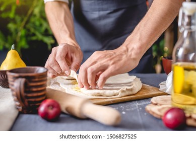 A man chef in a black apron kneads the dough with his hands for Christmas baking. Joyful cooking for festive Christmas and new year table - Powered by Shutterstock