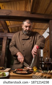 Man Chef Coocking Dishes On A Wooden Table In Restaurant