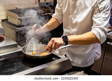 man chef cooking fried salmon fish in frying pan on kitchen - Shutterstock ID 2255025345