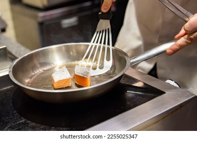 man chef cooking fried salmon fish in frying pan on kitchen - Shutterstock ID 2255025347